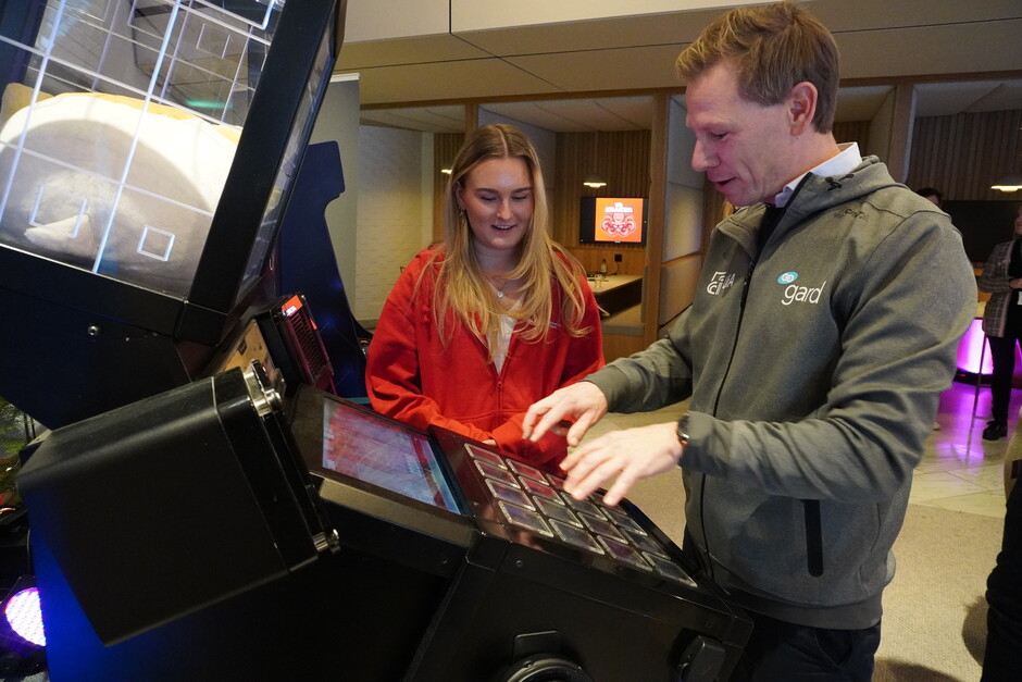 Akademisk E-sport-student Mia Pedersen fra Fevik instruerer drifts- og organisasjonsdirektør i Gard, Lars Lislegard-Bækken.  Foto: Zahir Mohamed